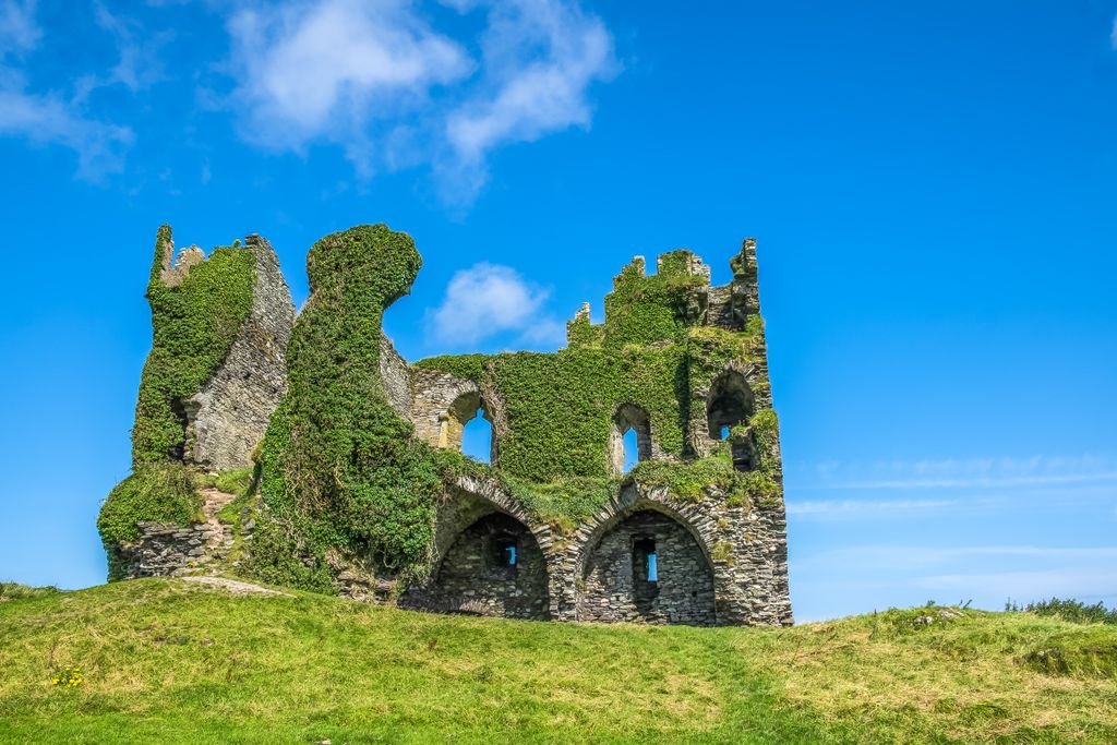Explore the enchanting ruins of Ballycarbery Castle in Cahersiveen, Ireland, under a clear summer sky.