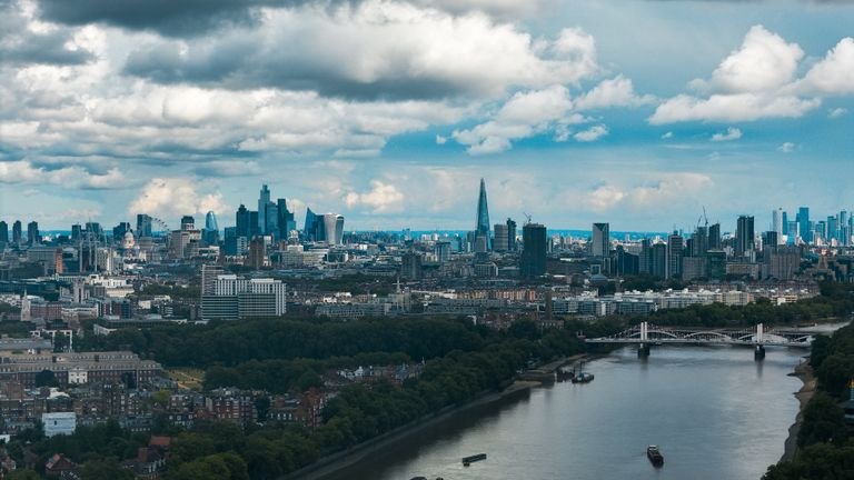 Wide-angle view of London's modern skyline and River Thames under a dramatic sky.